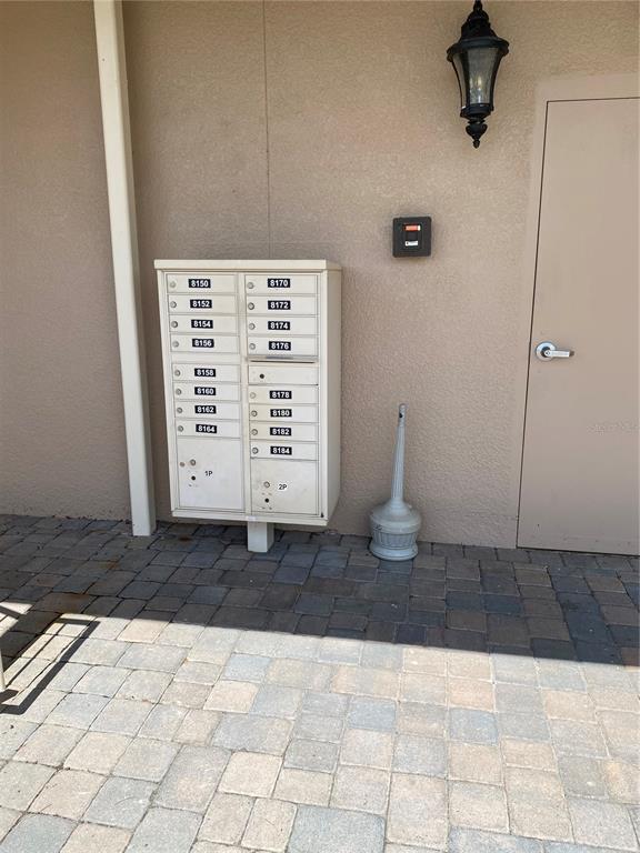 A wall-mounted cluster mailbox unit sits on a paved patio next to a door — 8176 SOUTHERN PINES DRIVE UNIT 8176, BROOKSVILLE, FL