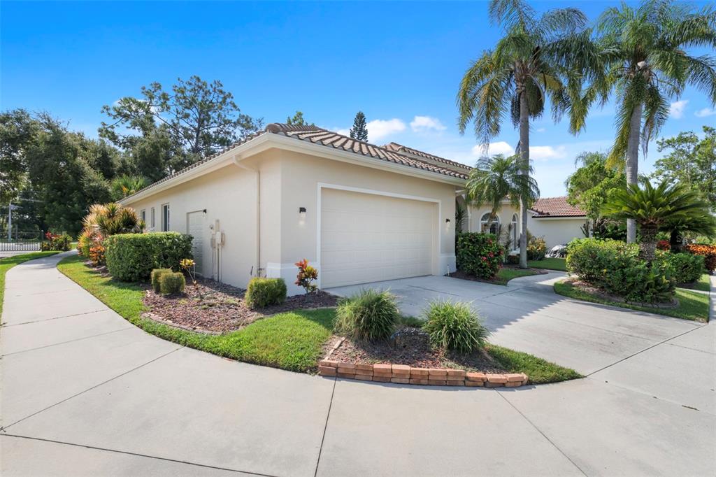 A beige single-story house with a two-car garage, tile roof, and landscaped front yard — 8809 HAVENRIDGE DRIVE, SARASOTA, FL