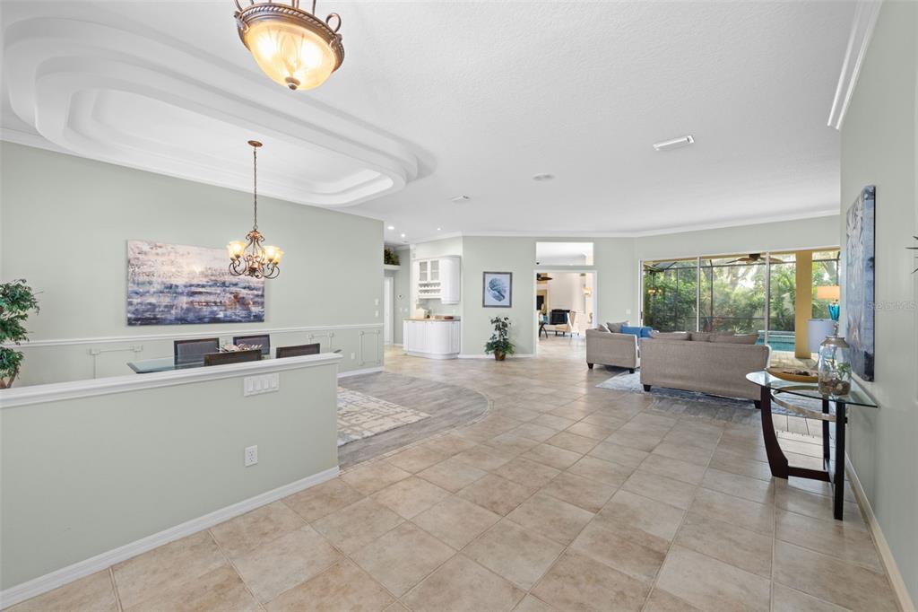 A spacious open-concept living and dining area features tile flooring, a tray ceiling, and windows — 8809 HAVENRIDGE DRIVE, SARASOTA, FL