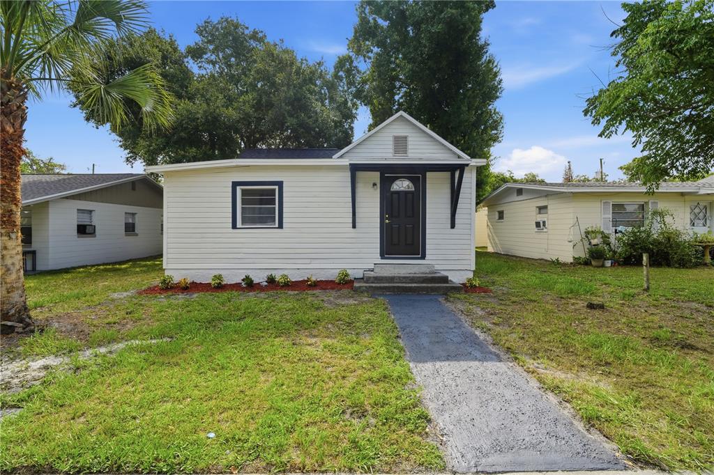 A small white house with a dark front door and a paved walkway in front — 515 NEW YORK AVENUE, ST CLOUD, FL