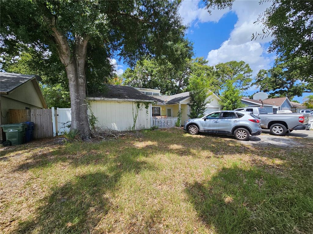 A single-story house with light siding, a white picket fence, and two vehicles parked outside — 4153 LANCASTER DRIVE, SARASOTA, FL
