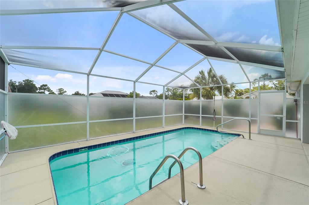 A screened-in swimming pool with a concrete deck and a metal frame enclosure — 9110 FLAGSTICK LANE, HUDSON, FL