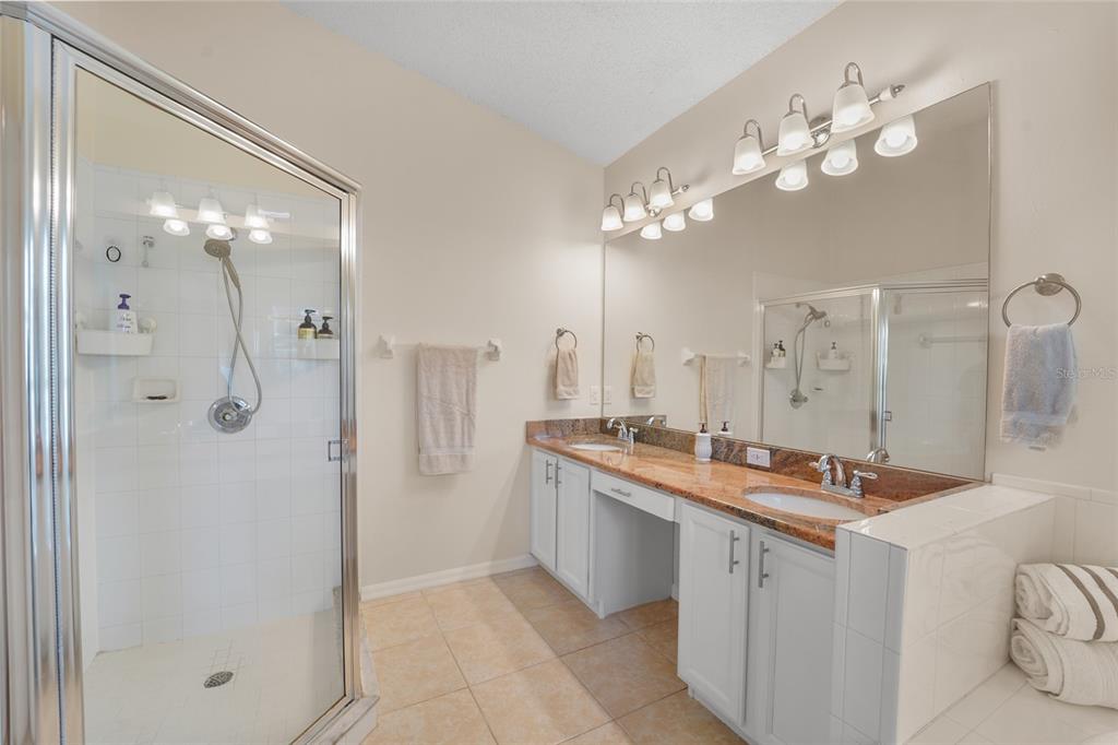 A bathroom features a glass-enclosed shower, a double vanity with granite countertops, and a mirror — 9110 FLAGSTICK LANE, HUDSON, FL