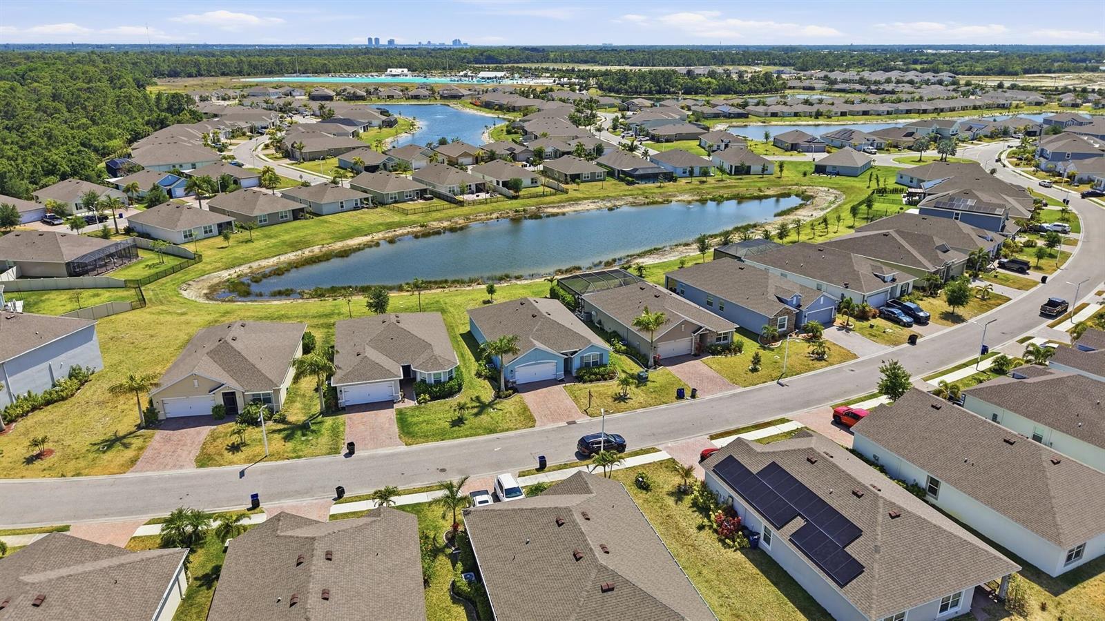 An aerial view of a suburban neighborhood featuring houses, a central pond, and streets — 8909 Cascade Price Circle, FL 33917, FL
