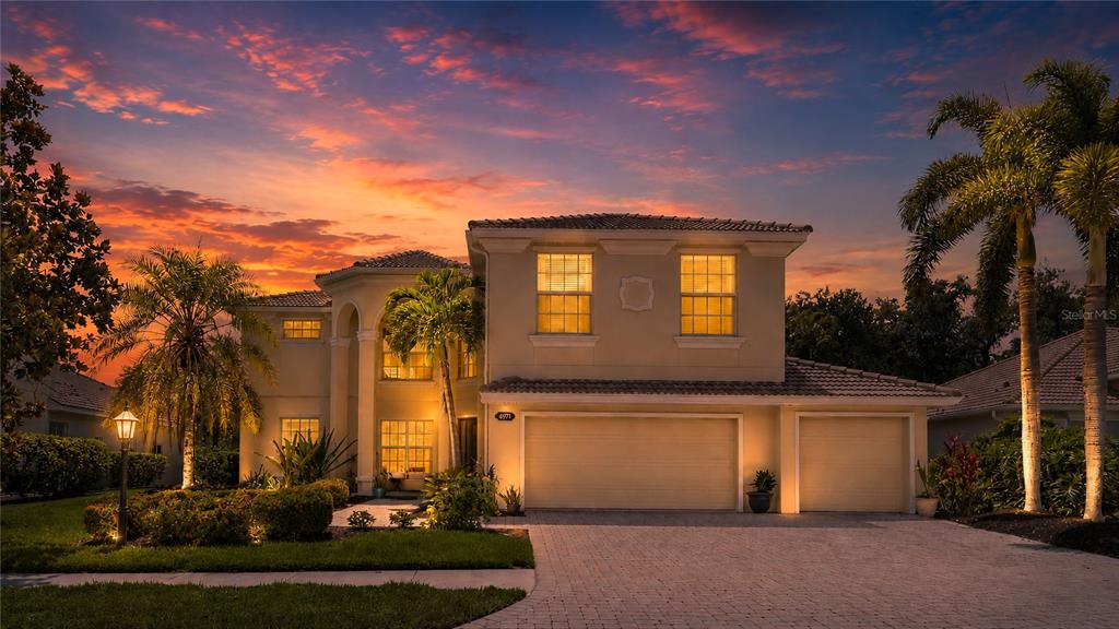 A two-story house with a three-car garage and palm trees at sunset — 6971 SCRUB JAY DRIVE, SARASOTA, FL