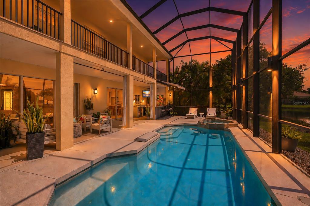 A two-story home features a screened-in pool and spa area at sunset — 6971 SCRUB JAY DRIVE, SARASOTA, FL