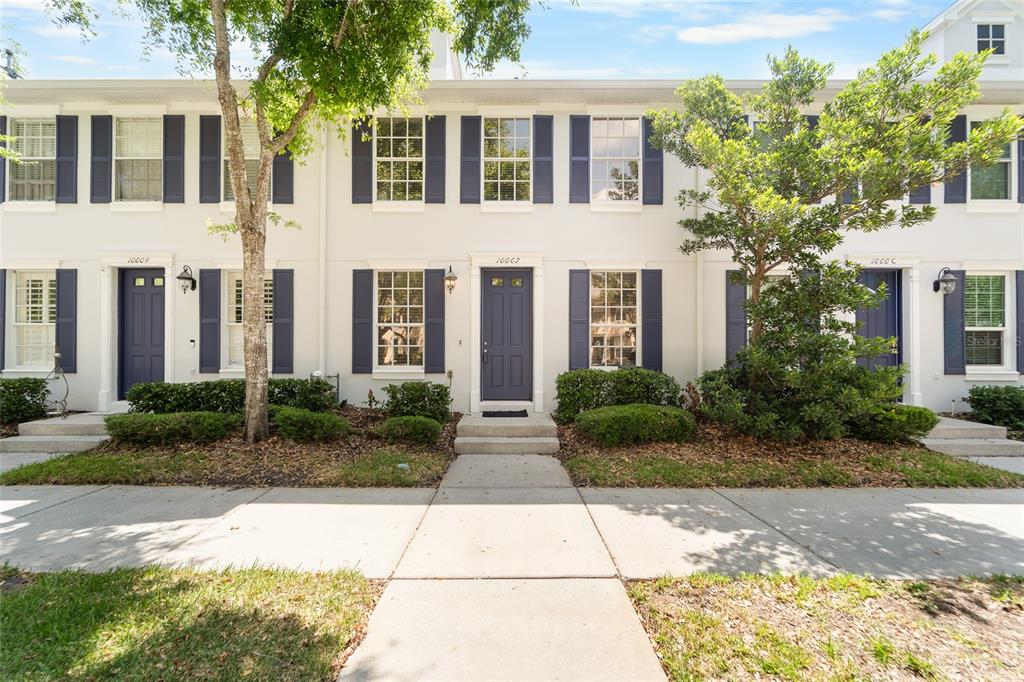 A row of three-story townhomes with white stucco walls, dark blue shutters, and front doors — 10007 BRADWELL PLACE, TAMPA, FL