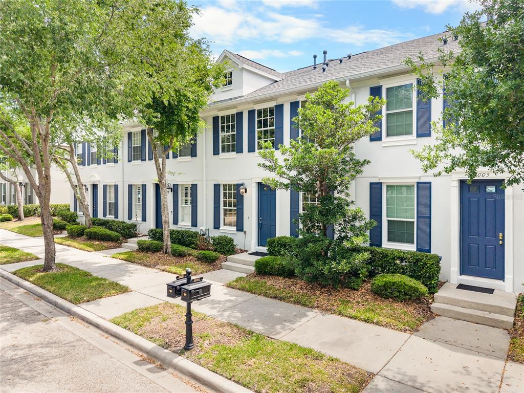 A row of white townhomes with blue shutters and doors along a sidewalk — 10007 BRADWELL PLACE, TAMPA, FL