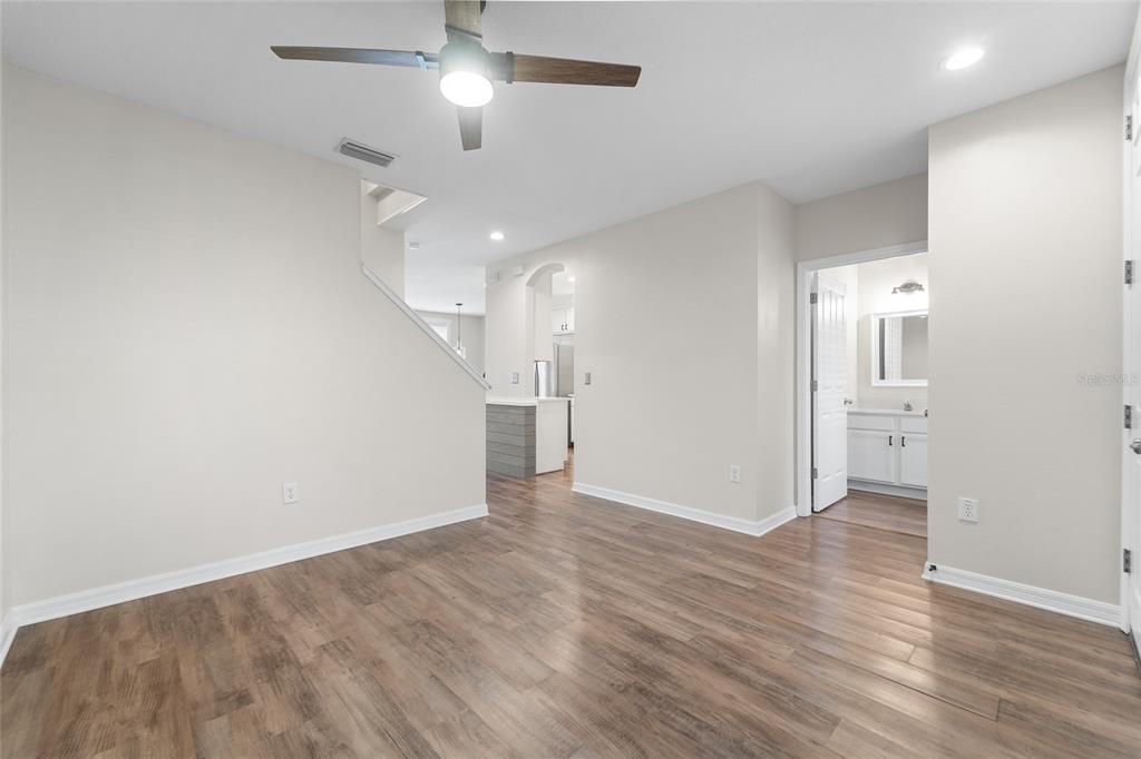 A room with wood-look flooring, a ceiling fan, and a doorway leading to a bathroom — 10007 BRADWELL PLACE, TAMPA, FL