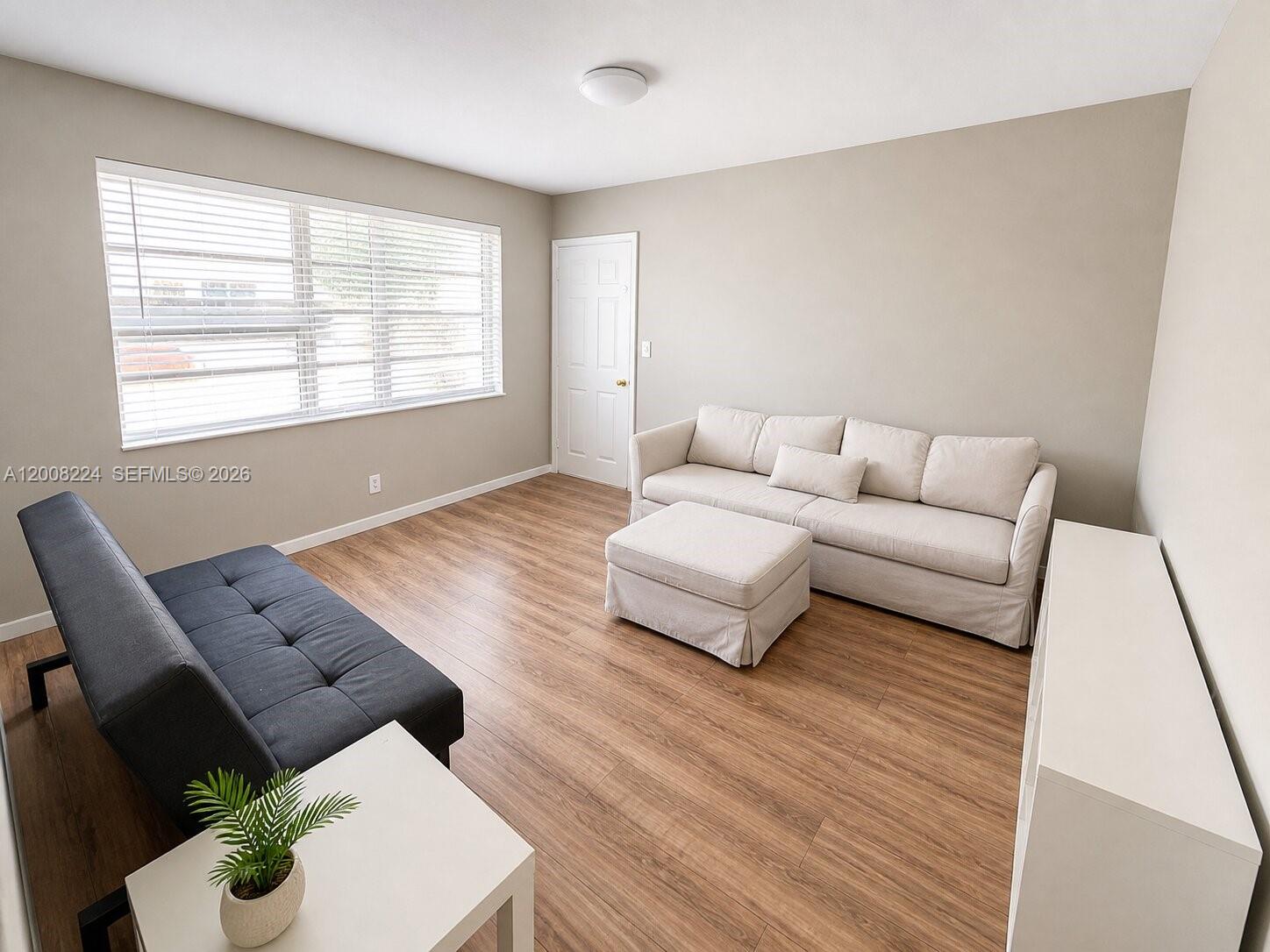 A living room features light-colored walls, wood-look flooring, a white sofa, and a dark futon — 375 SW 19th Ave # 1, Miami FL 33135, MIAMI, FL