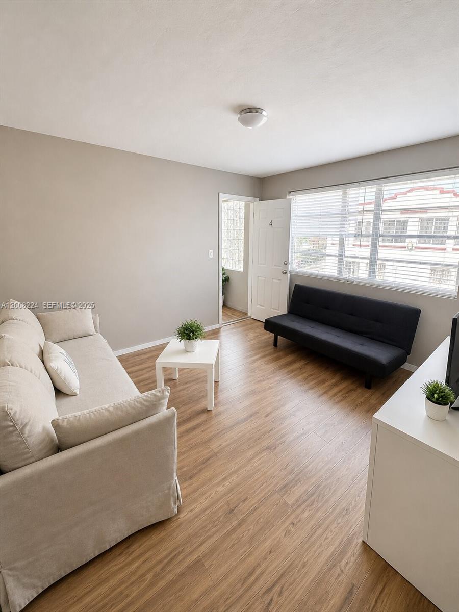 A living room features light wood-look flooring, a beige sofa, and a black futon — 375 SW 19th Ave # 1, Miami FL 33135, MIAMI, FL