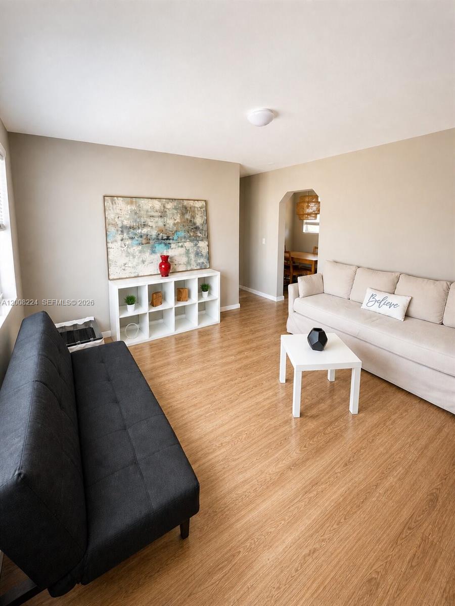 A living room features light wood flooring, a beige sofa, and a dark grey futon — 375 SW 19th Ave # 1, Miami FL 33135, MIAMI, FL