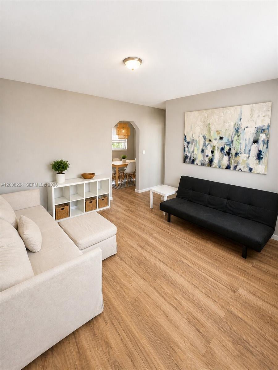 A living room features light wood-look flooring, a beige sofa, and a black futon — 375 SW 19th Ave # 1, Miami FL 33135, MIAMI, FL