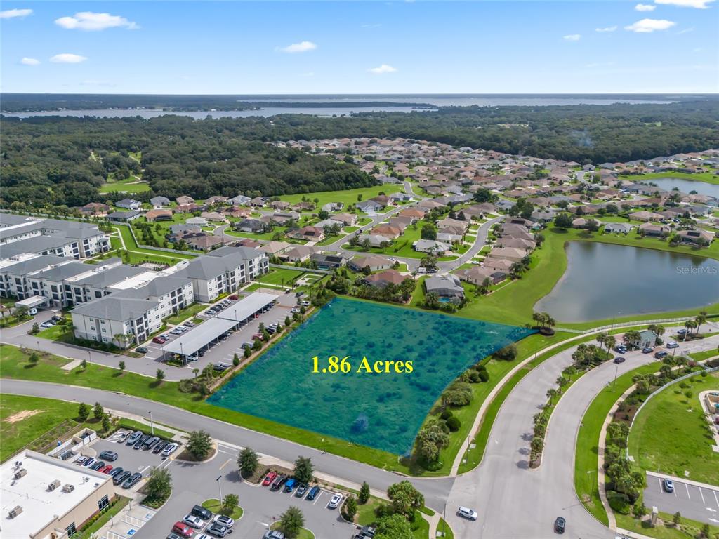 An aerial view shows a vacant 1.86-acre plot of land adjacent to residential and commercial buildings — 00 US HWY 441, SUMMERFIELD, FL