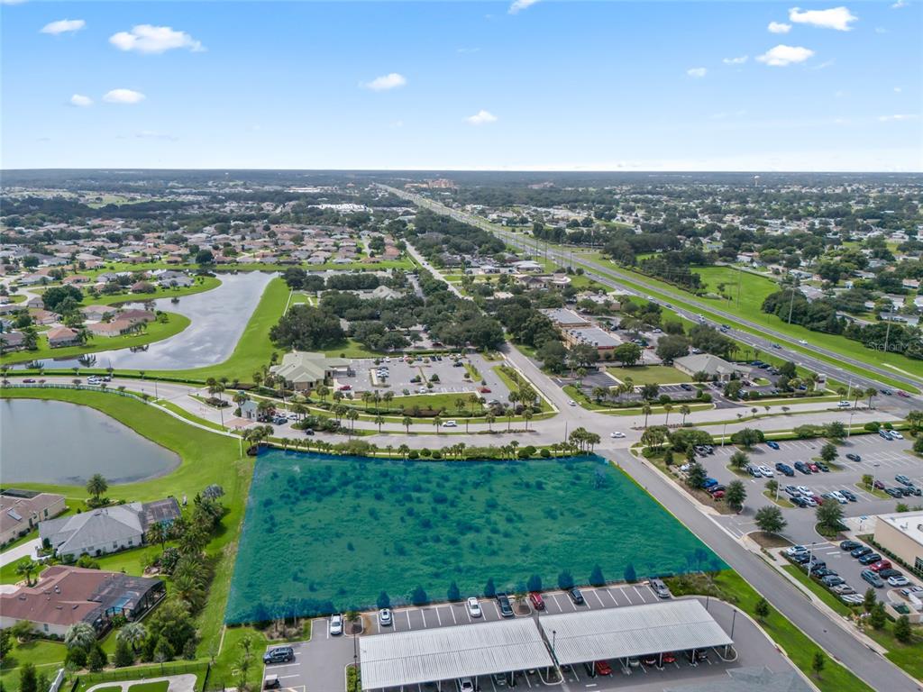 An aerial view shows a vacant, rectangular lot highlighted in green next to a parking lot — 00 US HWY 441, SUMMERFIELD, FL
