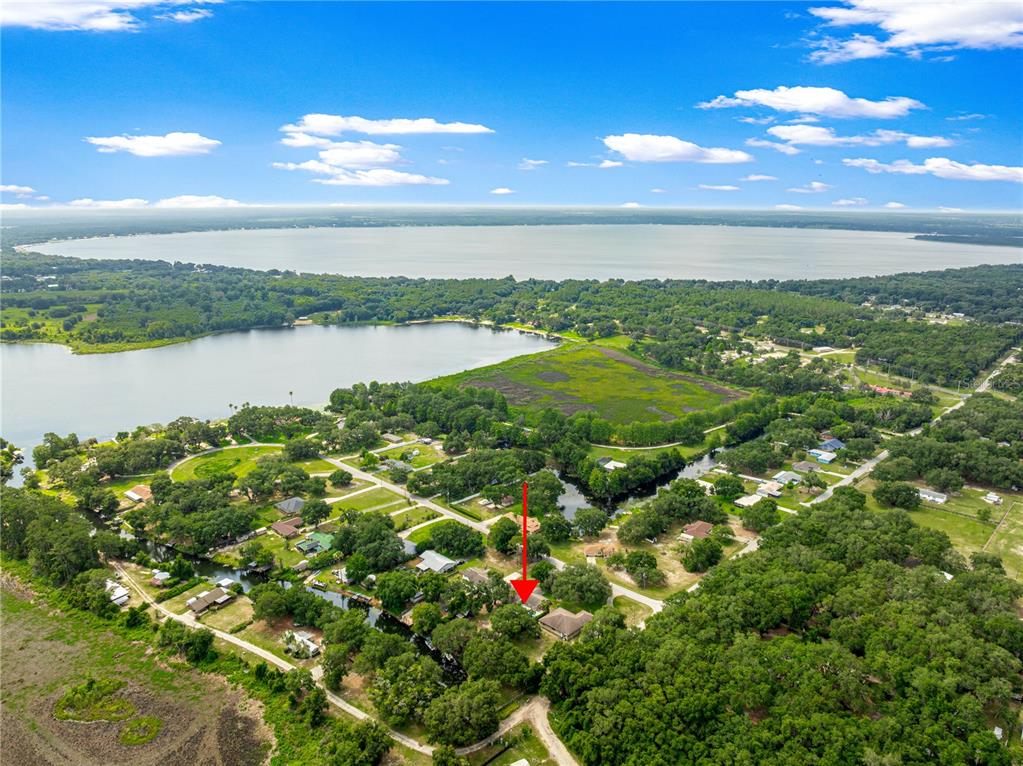 An aerial view shows a residential property marked by a red arrow near a lake — 11547 SE 123 ST, BELLEVIEW, FL