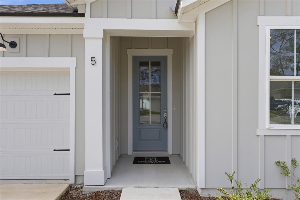 The exterior view shows a light gray house with a blue front door and garage — 5 REINE PLACE, PALM COAST, FL
