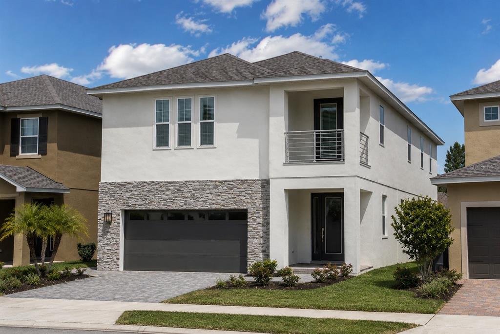 A two-story house with a stone-accented garage, white stucco exterior, and a second-floor balcony — 481 LASSO DRIVE, KISSIMMEE, FL