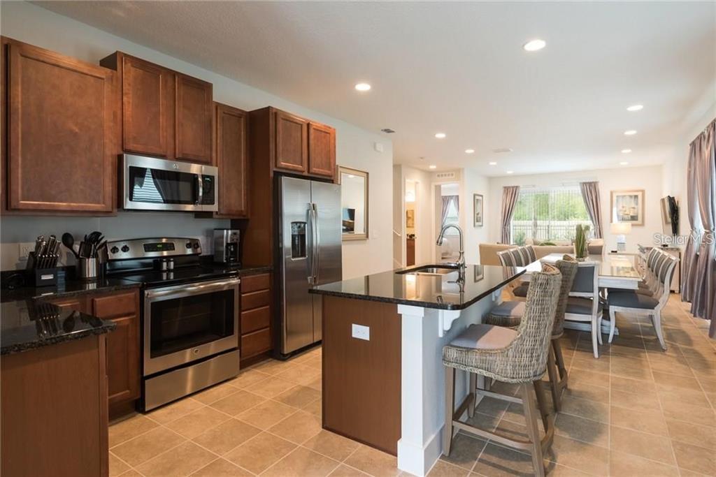 A kitchen with dark wood cabinets, stainless steel appliances, and an island with bar seating — 481 LASSO DRIVE, KISSIMMEE, FL