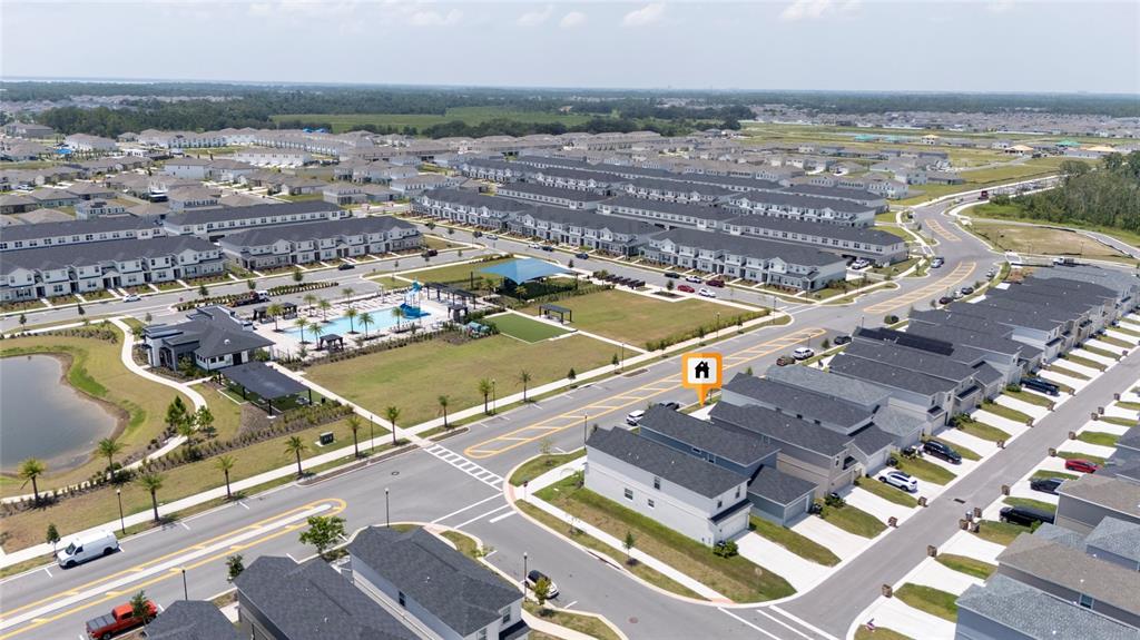 An aerial view shows a suburban neighborhood with a community pool, pond, and residential homes — 445 SILVERBELL TRAIL, ST CLOUD, FL