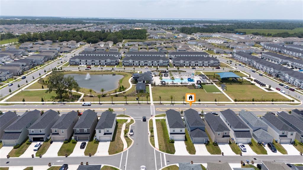 An aerial view shows a community pool, clubhouse, and green space surrounded by residential townhomes — 445 SILVERBELL TRAIL, ST CLOUD, FL