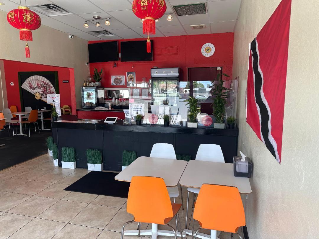 This restaurant interior features a service counter, orange and white chairs, and red walls — FORT LAUDERDALE, FL
