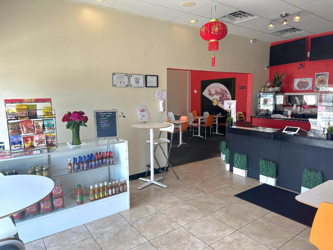 A restaurant interior features a service counter, a display case, tables, and a red lantern — FORT LAUDERDALE, FL