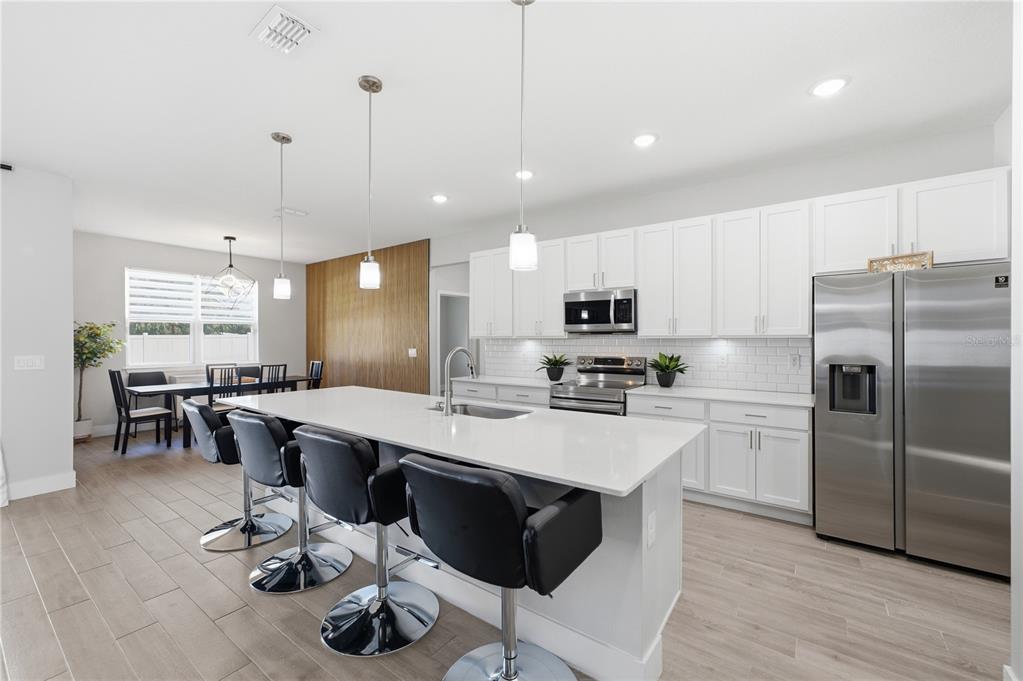 A modern kitchen features white cabinetry, stainless steel appliances, and a large island with seating — 2228 BANCROFT BOULEVARD, ORLANDO, FL