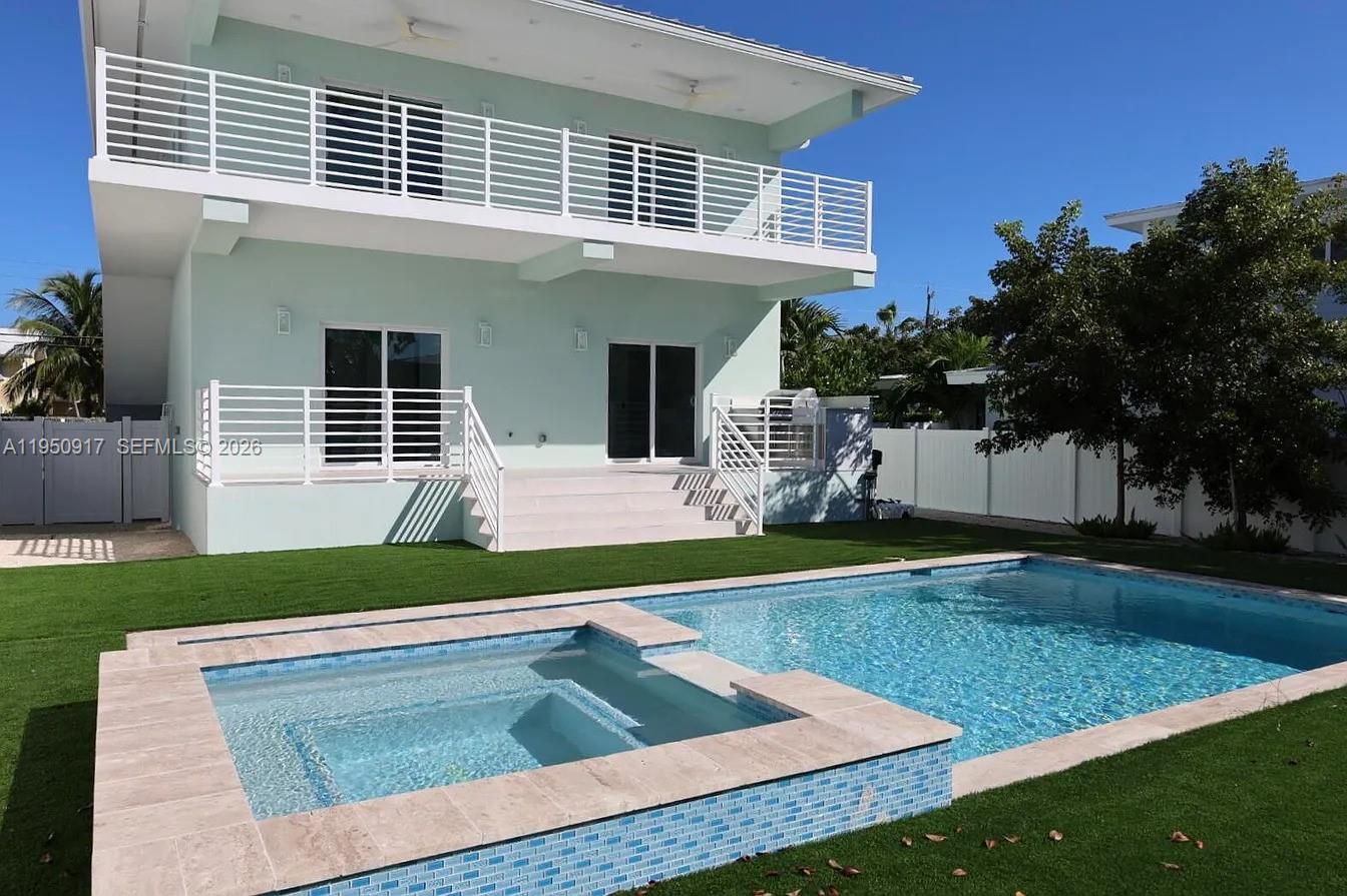 A two-story light green house features a backyard pool, spa, and white railings — 115 Azalea St, Plantation Key FL 33070, PLANTATION KEY, FL