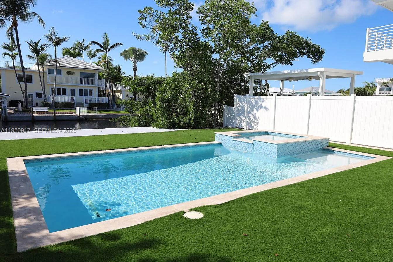 A backyard features a rectangular swimming pool with an integrated spa and artificial turf lawn — 115 Azalea St, Plantation Key FL 33070, PLANTATION KEY, FL
