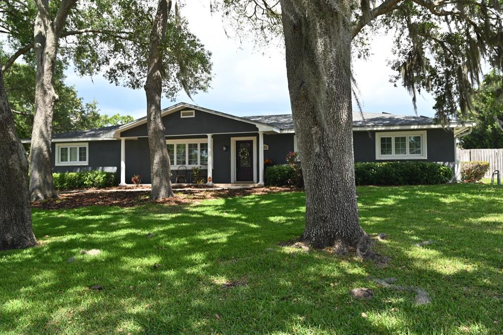 A dark gray single-story house with white trim and large oak trees in the yard — 1311 ESTATEWOOD DRIVE, BRANDON, FL