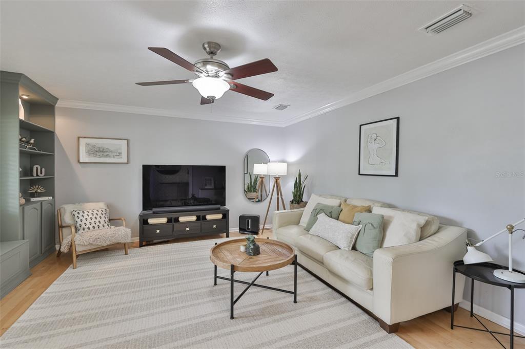 A living room features a beige sofa, a round wooden coffee table, and a television — 1311 ESTATEWOOD DRIVE, BRANDON, FL