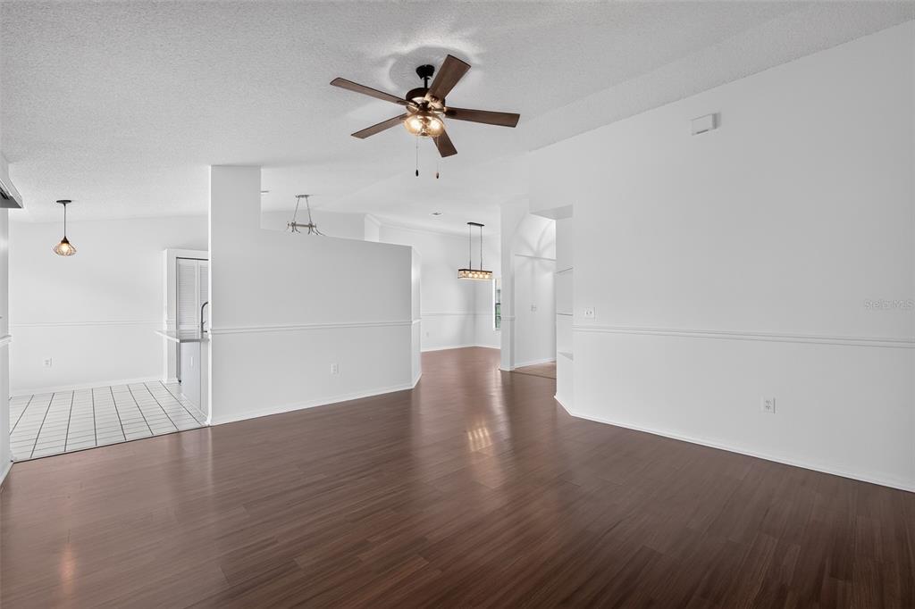An open living area features wood-look flooring, white walls, and a ceiling fan — 511 BASIL COURT, POINCIANA, FL