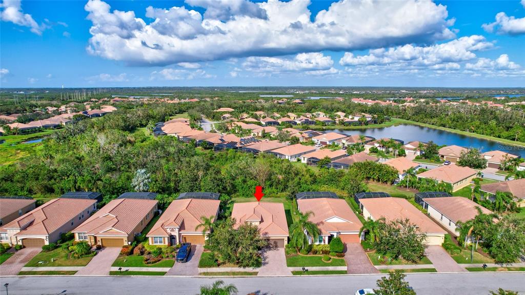 An aerial view shows a row of suburban houses with tile roofs and a red arrow — 9019 HERITAGE SOUND DRIVE, BRADENTON, FL