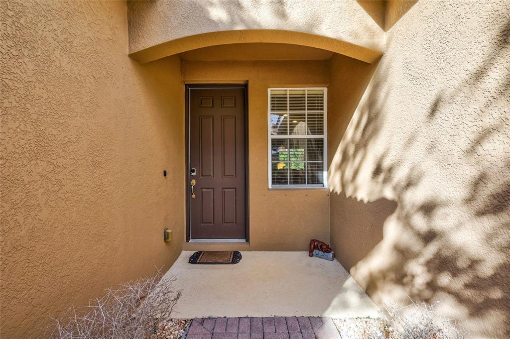 A brown front door and a window are set into a tan stucco exterior entryway — 9019 HERITAGE SOUND DRIVE, BRADENTON, FL