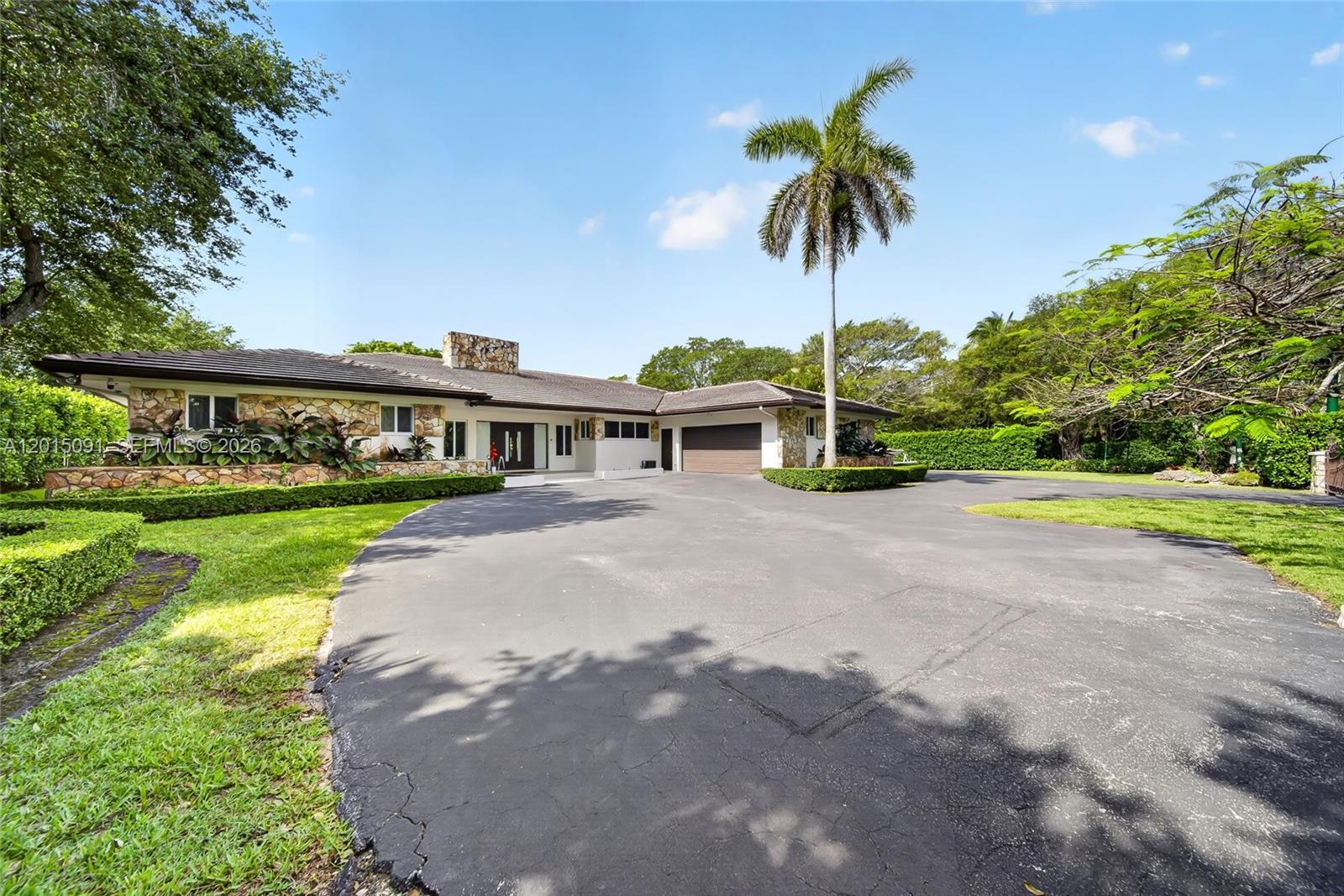 A single-story house with stone siding and a large circular driveway sits under a palm tree — 6650 SW 112th St, Pinecrest FL 33156, PINECREST, FL