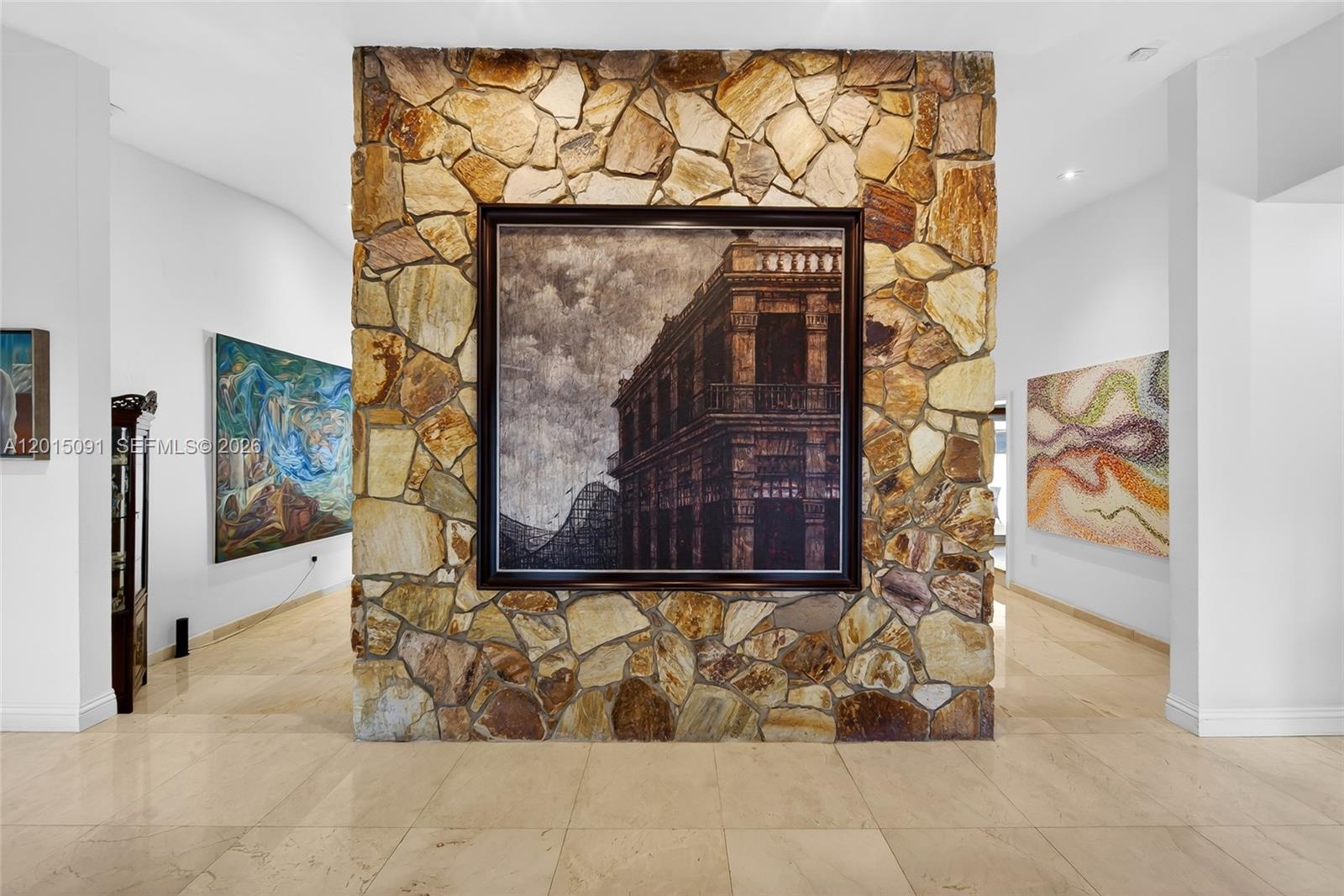 A stone-clad wall features a large framed painting in a room with tiled floors — 6650 SW 112th St, Pinecrest FL 33156, PINECREST, FL