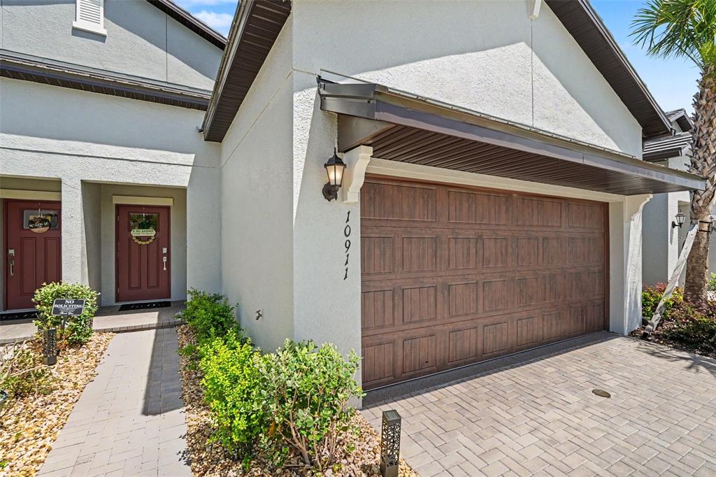 The exterior of a house features a brown garage door, a front entrance, and pavers — 10911 RUSTIC EVE COURT, LAND O LAKES, FL