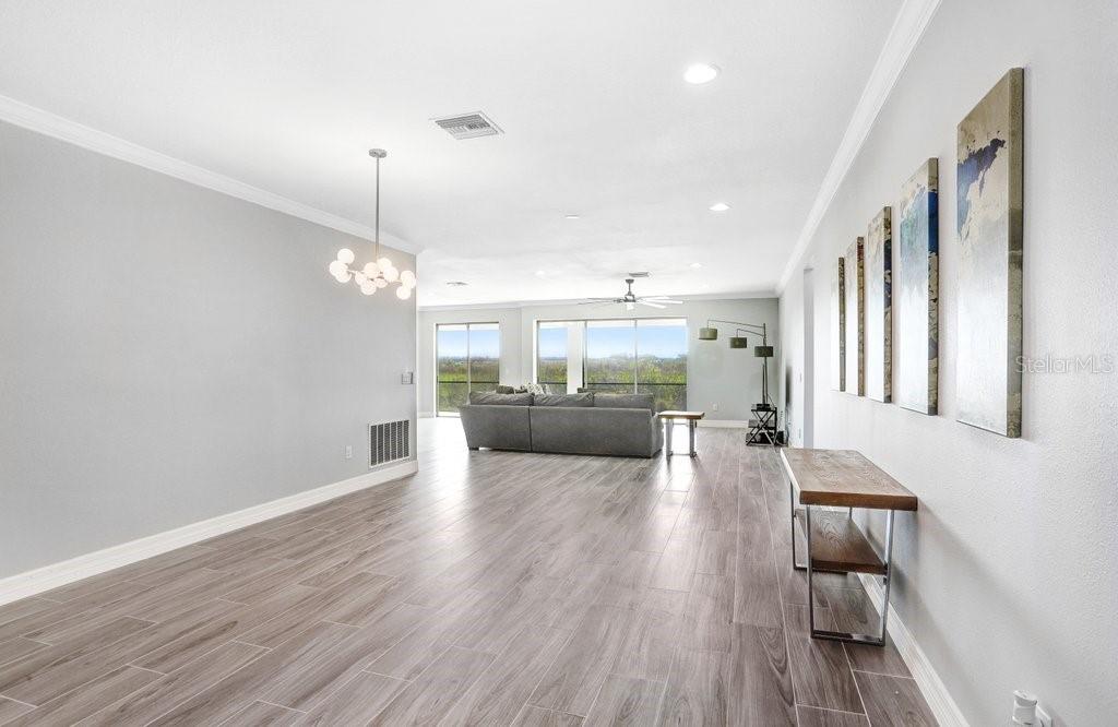 A spacious living area features light wood-look flooring, a grey sectional sofa, and wall art — 11677 BRIGHTON KNOLL LOOP, RIVERVIEW, FL