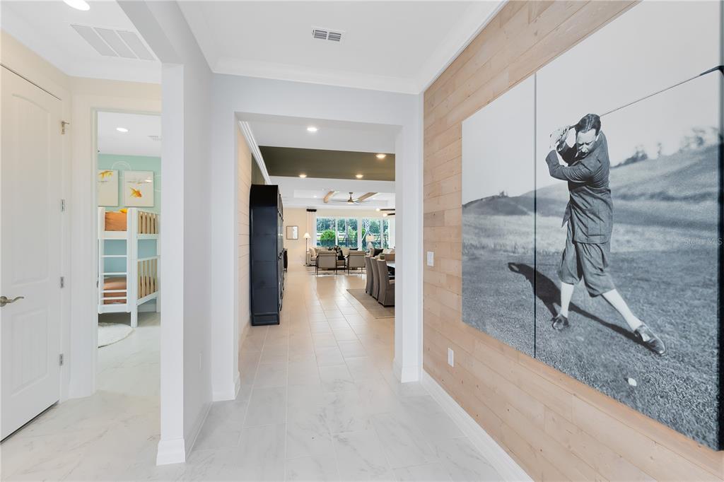A hallway with light tile flooring leads to an open living area featuring wood-paneled walls — 5237 HANDSOME HILLS DRIVE, MOUNT DORA, FL