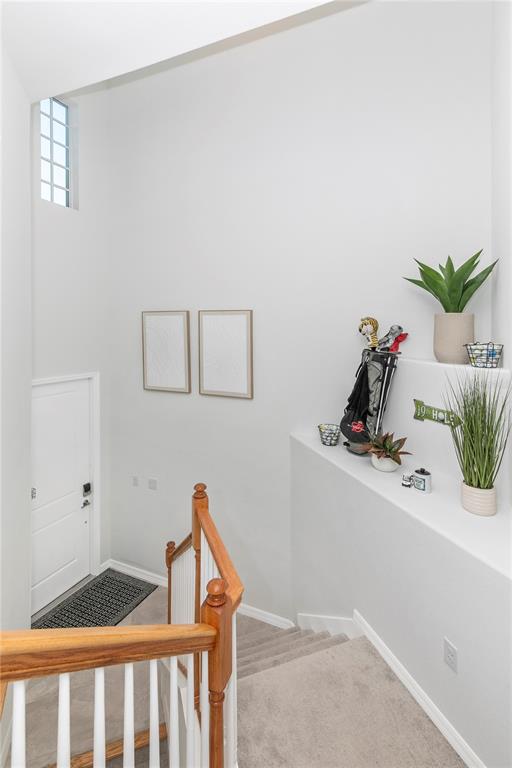 A staircase with a wooden railing leads down to a white door and entryway — 17560 BORACAY COURT UNIT 202, VENICE, FL