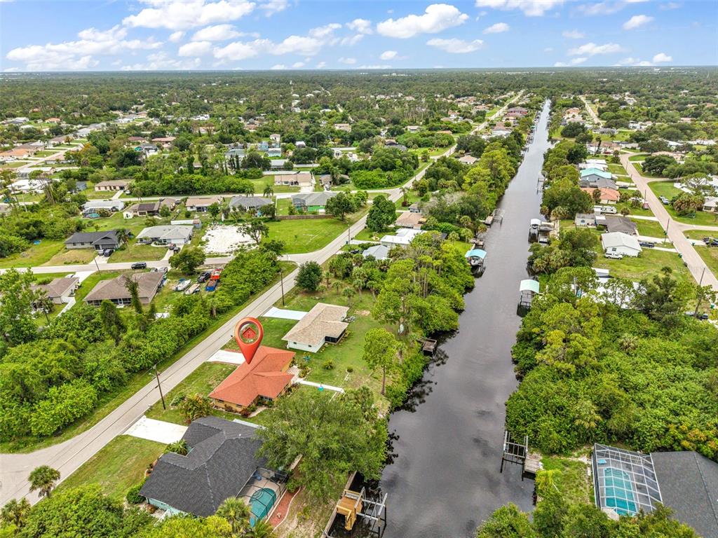 An aerial view shows a house with a red roof situated along a canal — 2626 AUBURN BOULEVARD, PORT CHARLOTTE, FL
