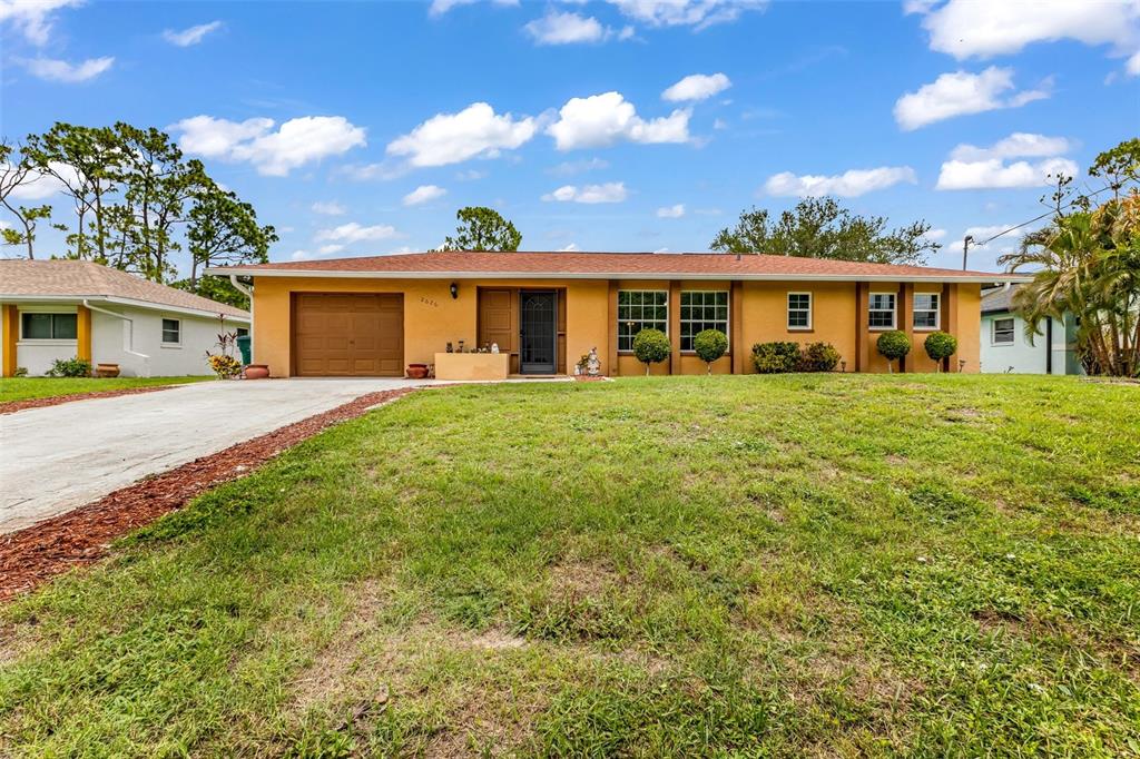 A single-story yellow house with a brown roof and a concrete driveway — 2626 AUBURN BOULEVARD, PORT CHARLOTTE, FL