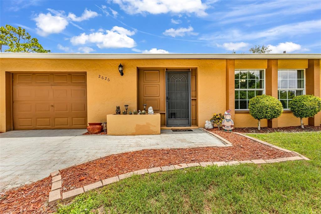 The exterior of a single-story house features a garage, a front entrance, and landscaping — 2626 AUBURN BOULEVARD, PORT CHARLOTTE, FL