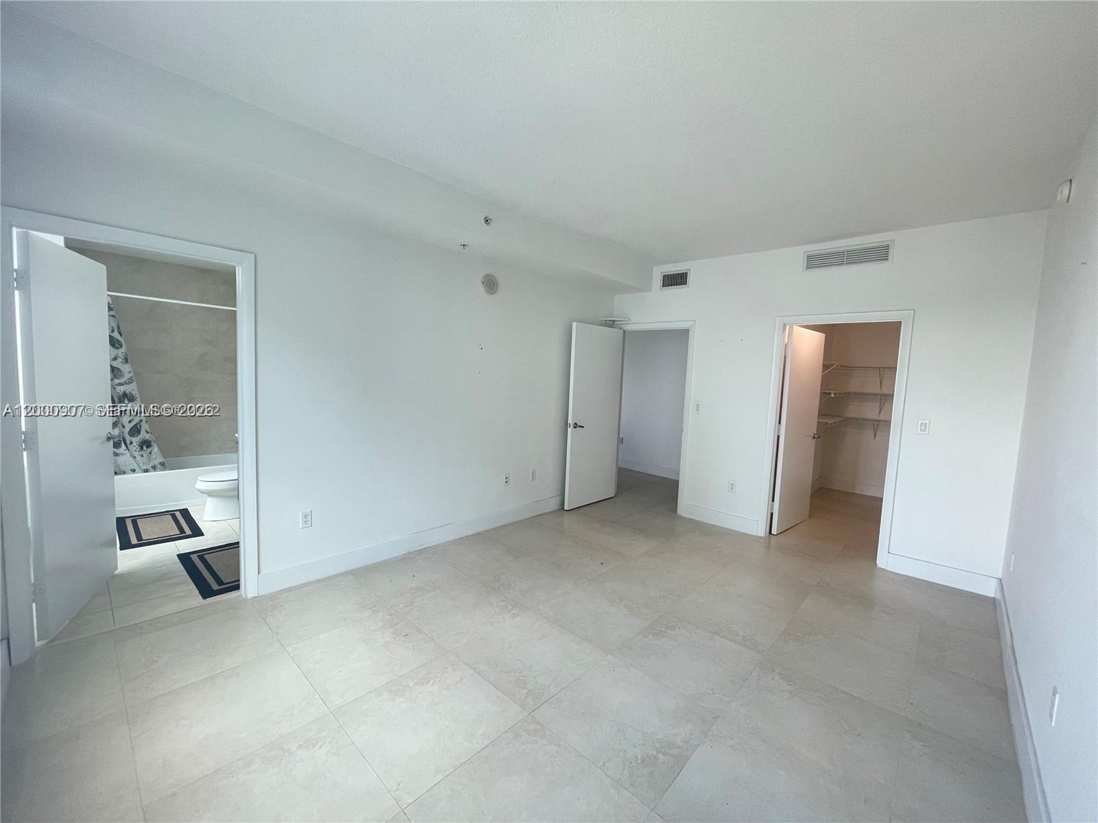 A bedroom with light tile flooring, a bathroom, a closet, and two interior doors — 1900 N Bayshore Dr # 3311, Miami FL 33132, MIAMI, FL