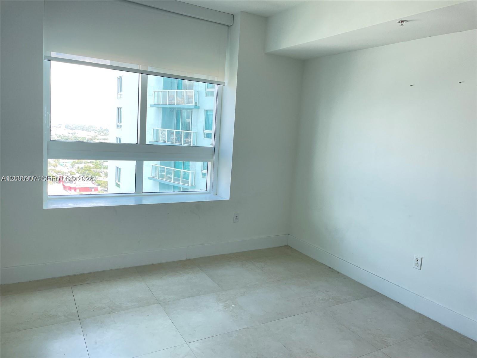 An empty room features white walls, light-colored tile flooring, and a large window with blinds — 1900 N Bayshore Dr # 3311, Miami FL 33132, MIAMI, FL