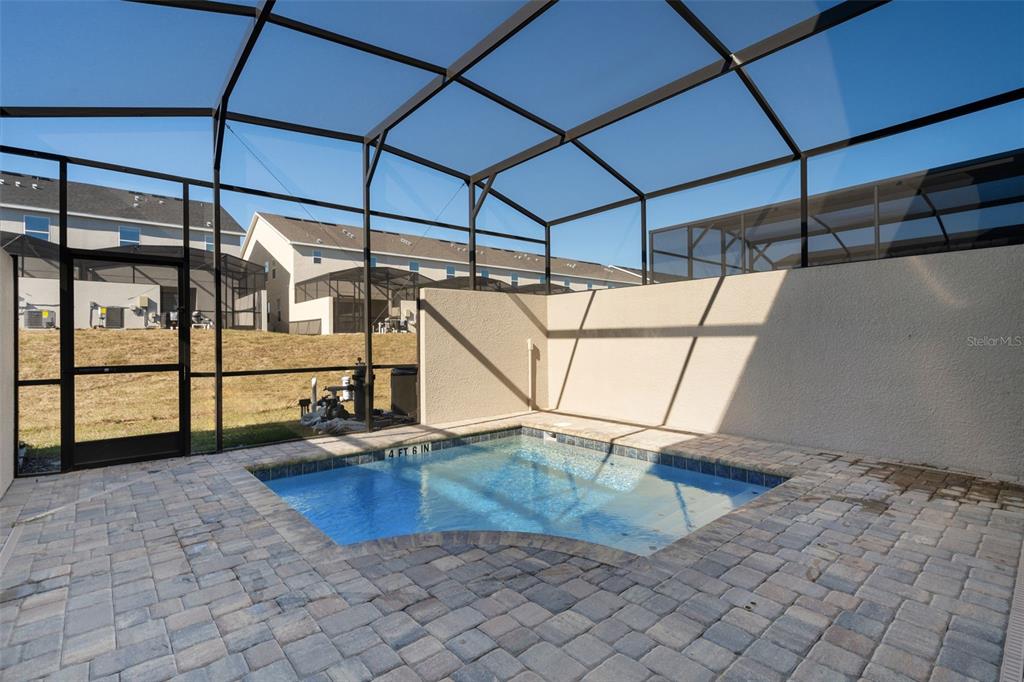 A small pool with a paver deck is enclosed by a screened lanai and wall — 2358 ZABALLINA PLACE, KISSIMMEE, FL