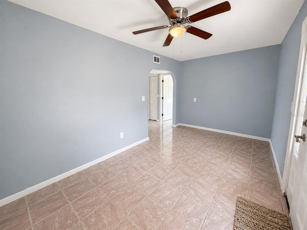 A room with light blue walls, a ceiling fan, and beige tiled flooring — 4824 LIMESTONE DRIVE, PORT RICHEY, FL