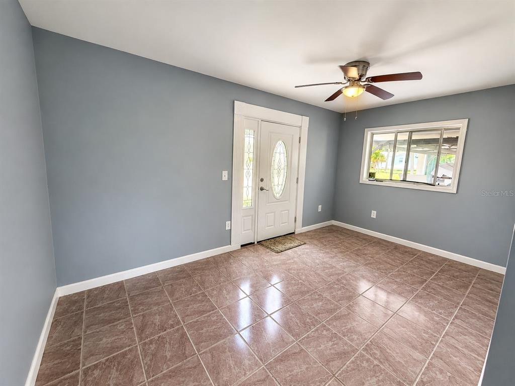 An entryway features blue walls, tile flooring, a white front door, and a ceiling fan — 4824 LIMESTONE DRIVE, PORT RICHEY, FL