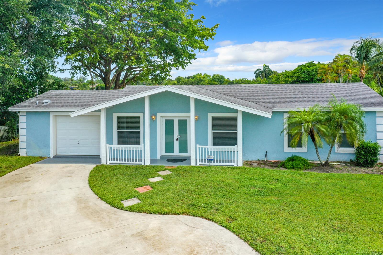 A light blue, single-story house with a white garage door and a front lawn — 6803 Kingston Drive, Lake Worth FL 33462, LAKE WORTH, FL